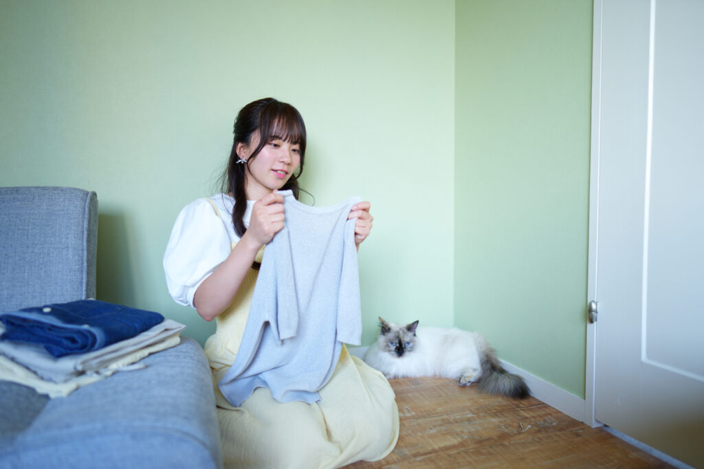 洗濯物をたたむ飼い主さんの横でリラックスしてる猫